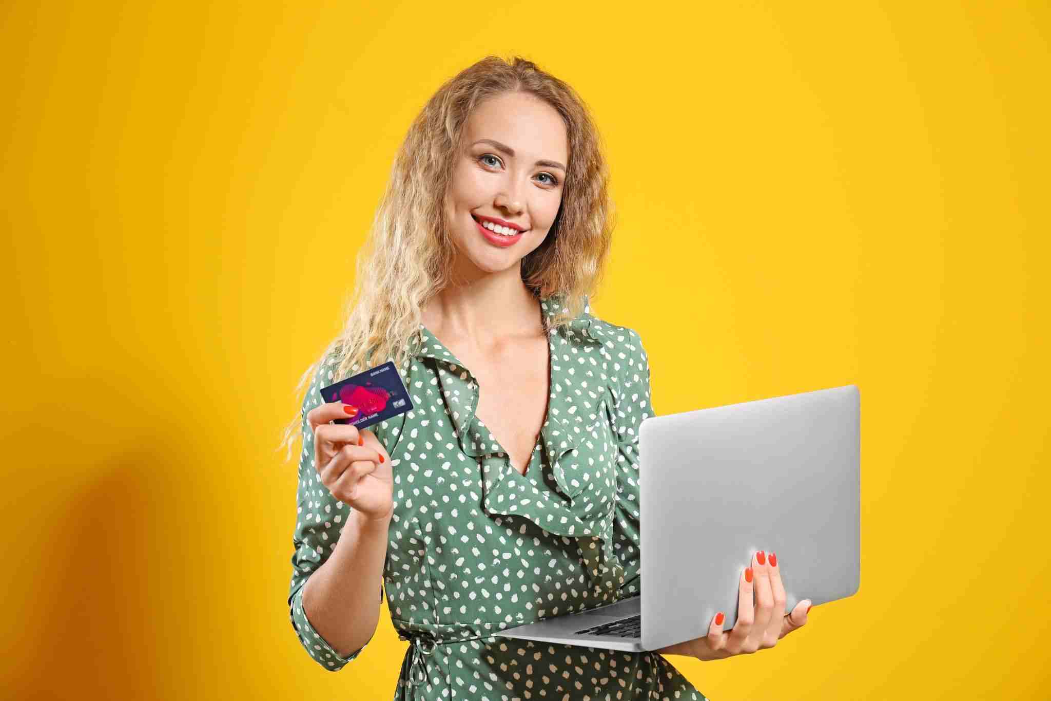 young woman holding a laptop and a credit card