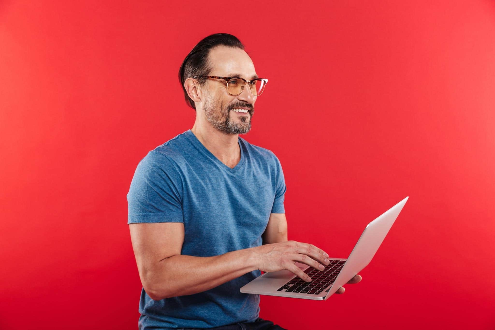 man holding laptop in a red background