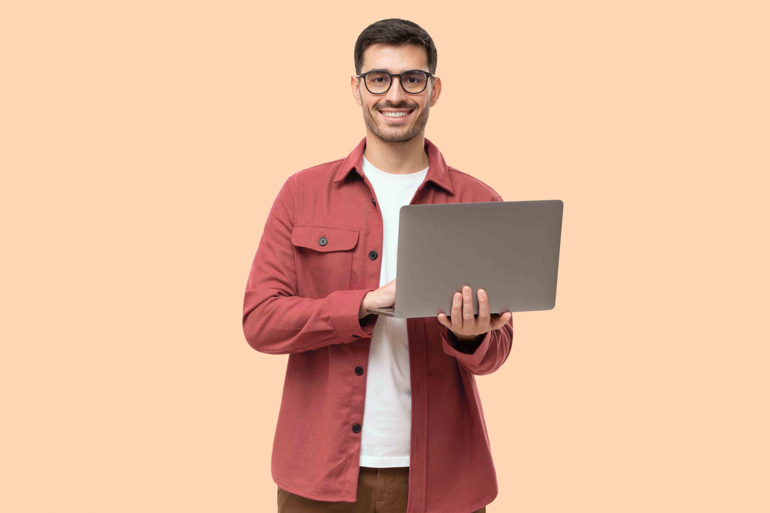 Young man standing holding laptop and looking at camera with a happy smile