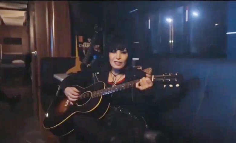 female rock star playing the guitar while sitting