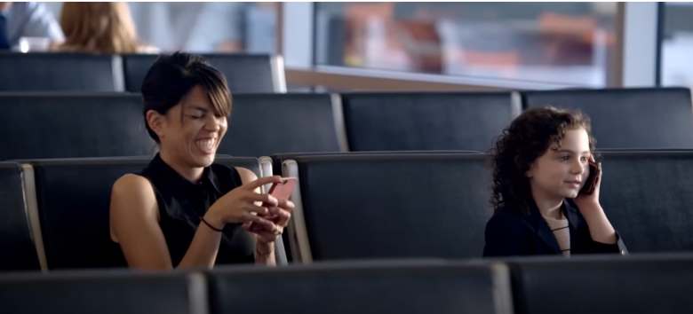 adult female and a little girl using cellphones at an airport