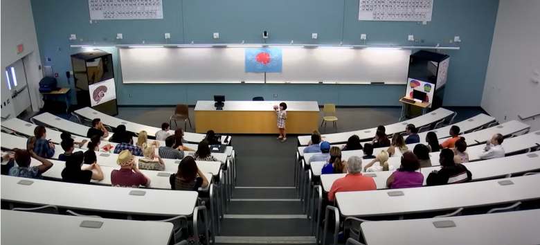 little girl giving a lecture in a classroom full of adults