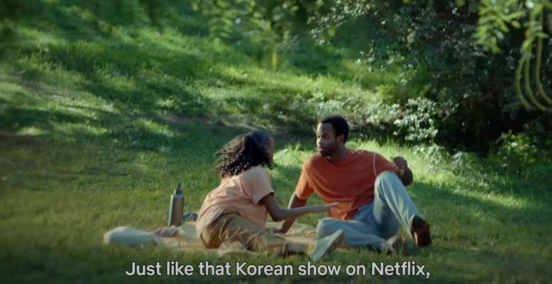 young black couple having a picnic on an open field on a sunny day