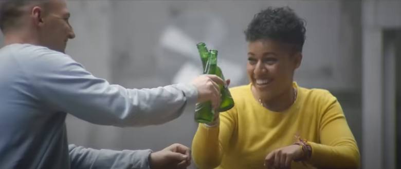 man and woman drinking a bottle of beer together