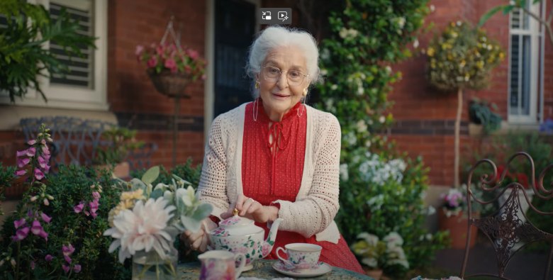 senior woman in a red dress sitting at a table drinking tea