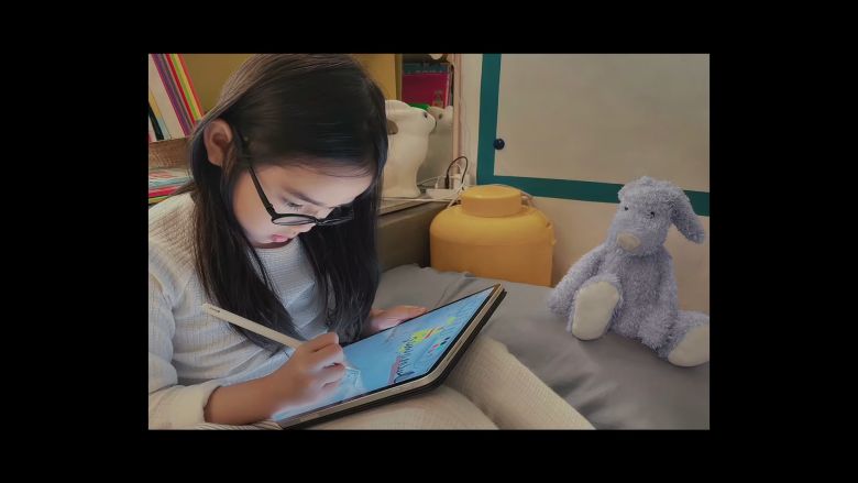 Small asian child writing on an ipad