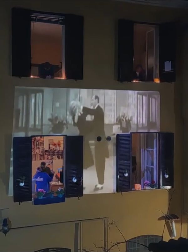 four windows open in a building with a couple dancing inside one of the apartment