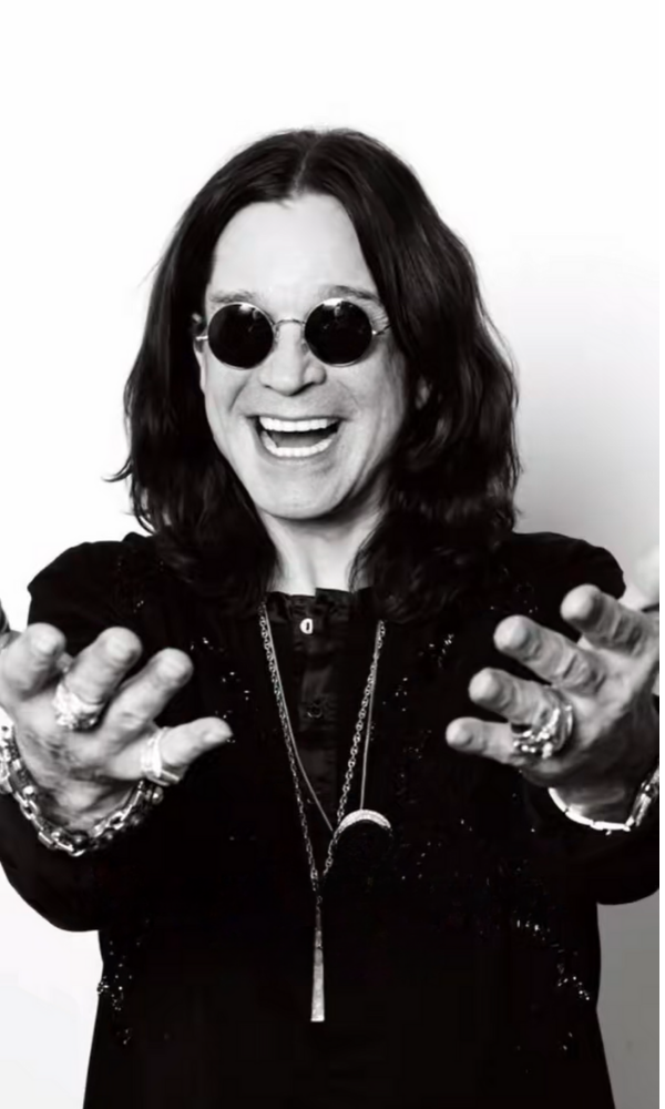 Smiling Ozzy Osbourne in black and white with outstretched hands