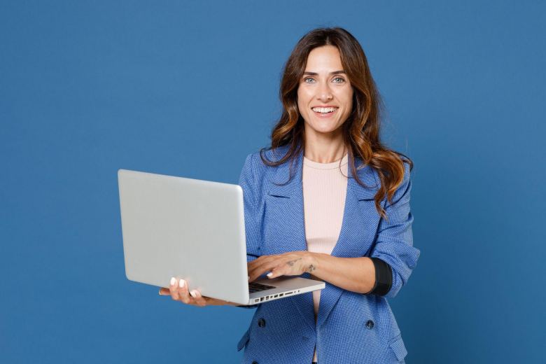 blue-eyed woman in a jacket holding a laptop