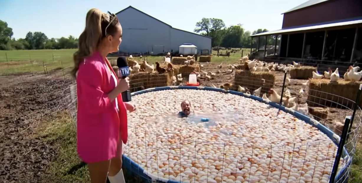female reporter in a pink jacket and a man in an egg pool on a farm