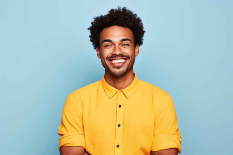 young black man in a yellow shirt smiling