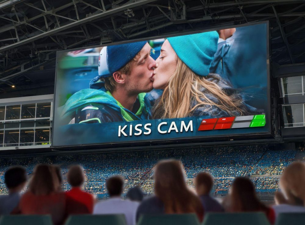 Couple kissing displayed on stadium kiss cam screen