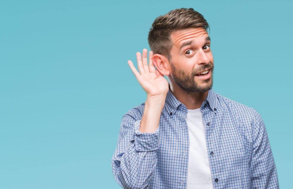 Man gesturing to improve hearing with hand to ear