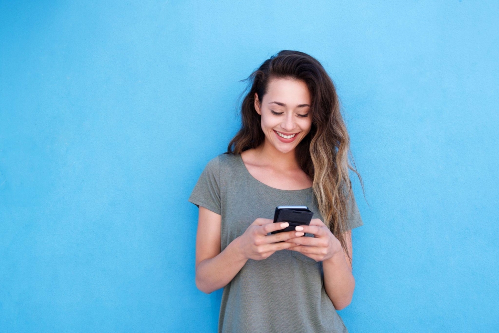 Smiling woman with smartphone against blue background