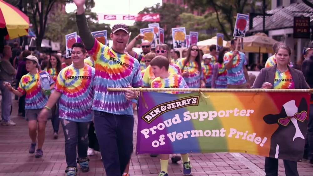 Ben & Jerry's supporters in tie-dye shirts marching with pride banner in Vermont parade