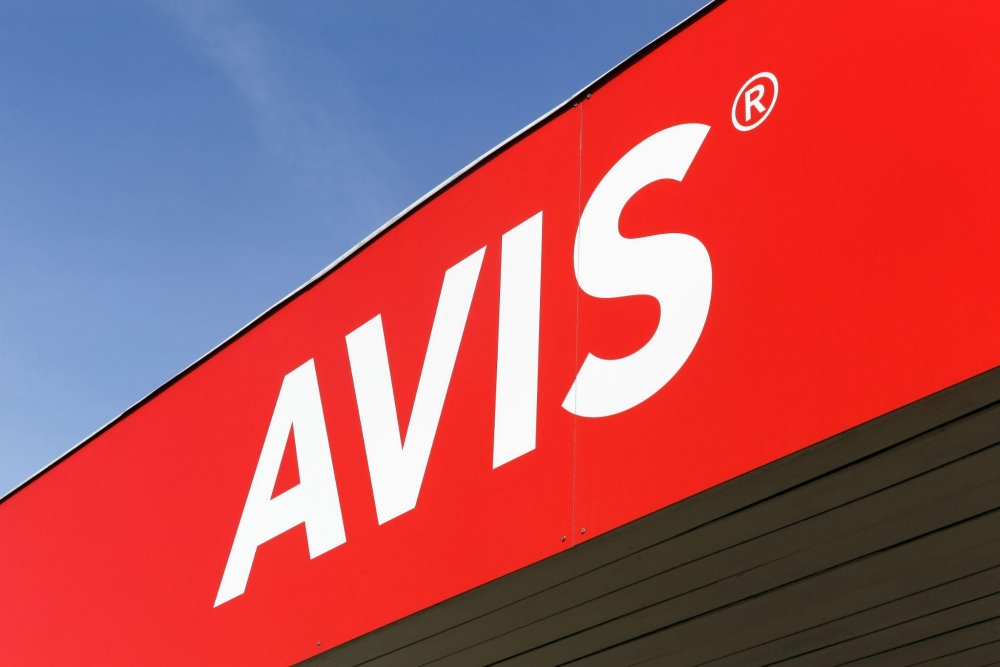 Bright red Avis sign against a clear blue sky