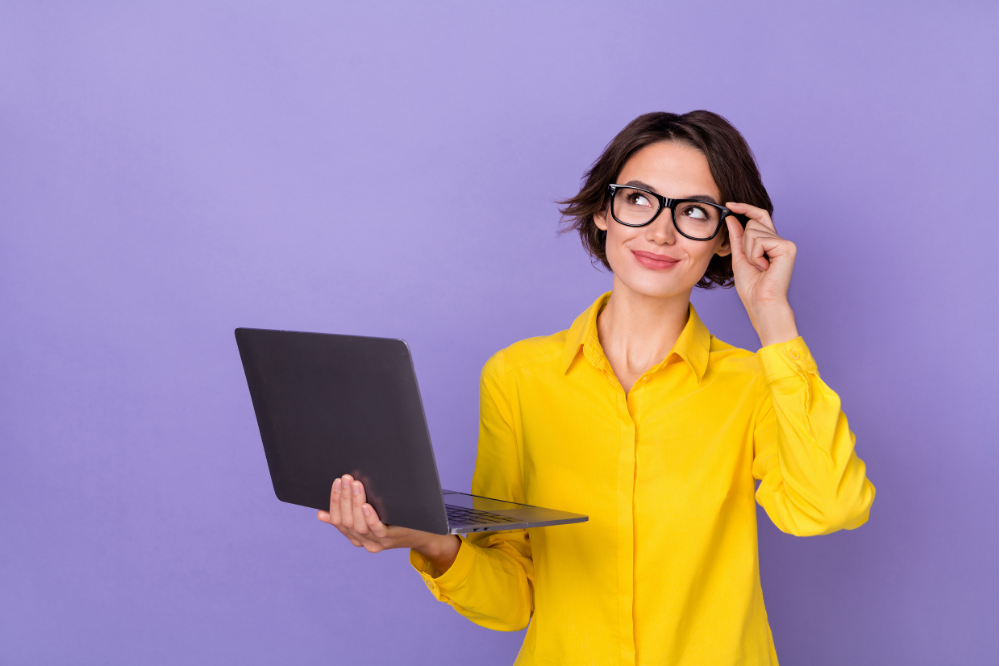 Thoughtful woman with glasses, laptop in hand