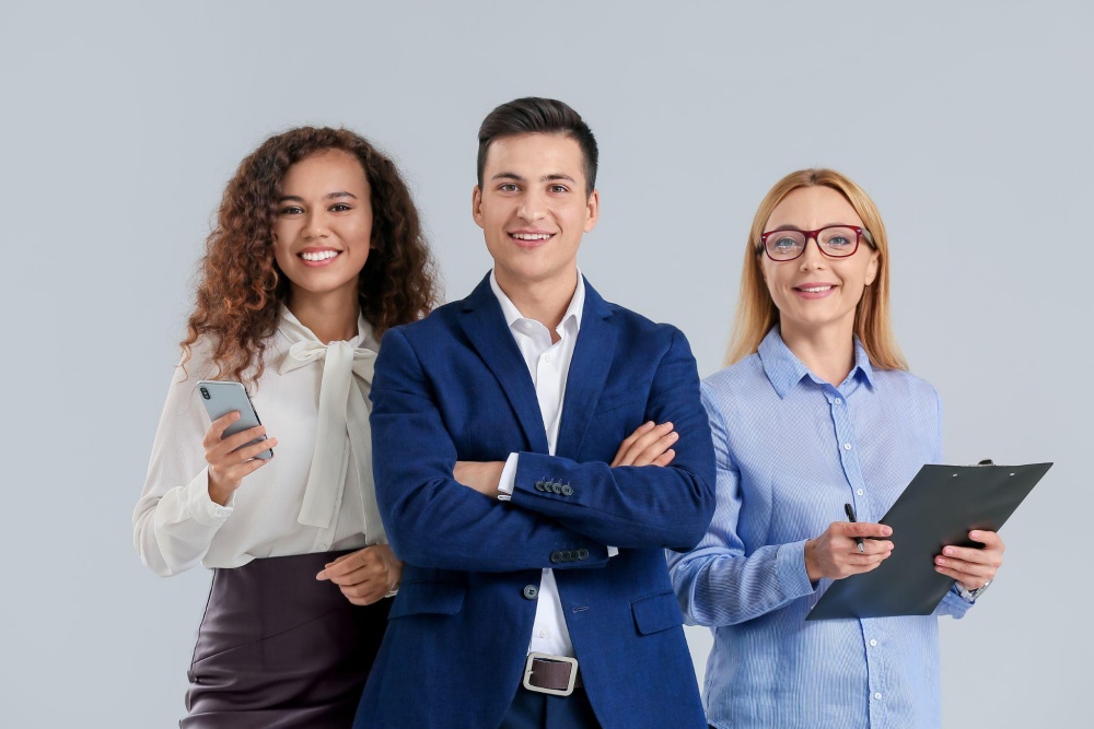 Three professionals smiling, holding phone and clipboard