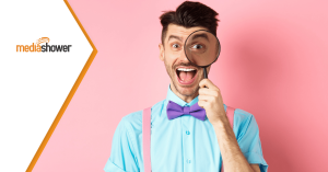 Happy guy in suspenders holding magnifying glass on pink