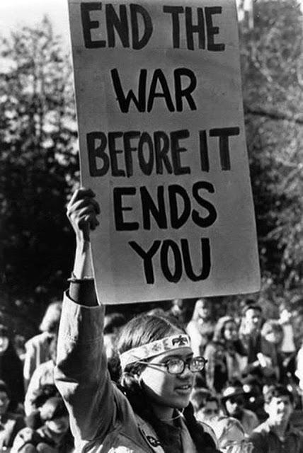 Protest sign reading 'End the War Before It Ends You' held by a person in a crowd