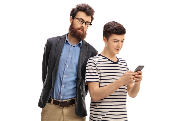 Father looking over his teenage sons shoulder.