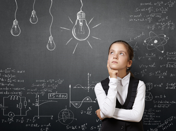 Female student in front of chalkboard appearing in deep thought.