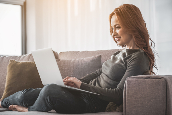 Woman sitting on her couch looking at her laptop computer.