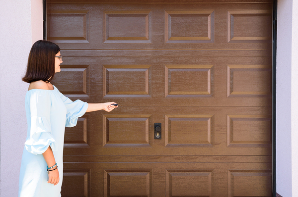 Woman pointing remote at a garage door