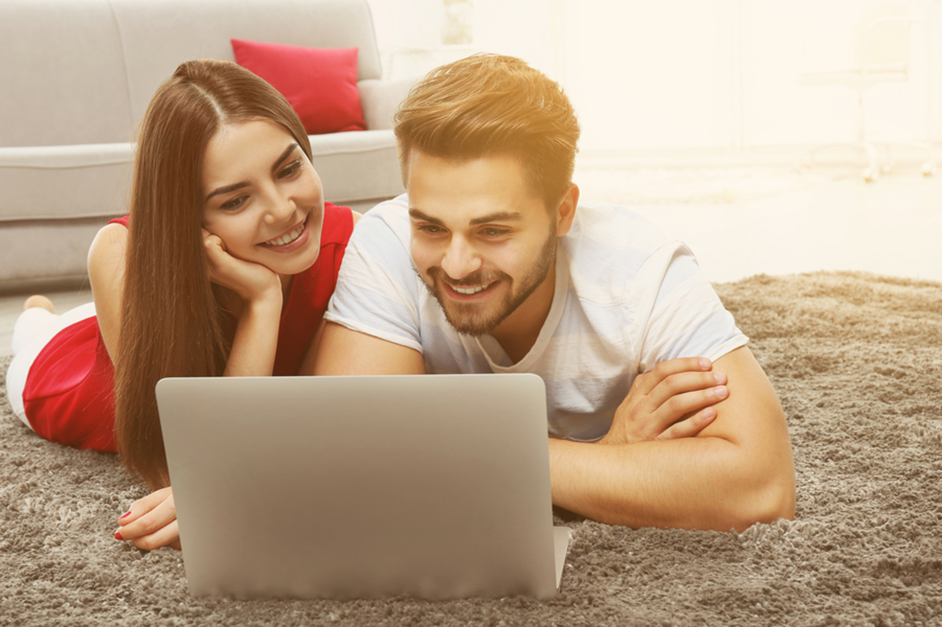 Couple lying on the floor looking at a laptop together. Couple lying on the floor looking at a laptop together.