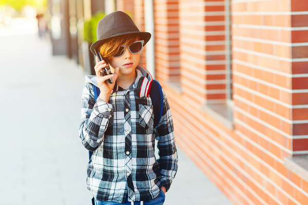 Young teenager walking outside and using his phone.