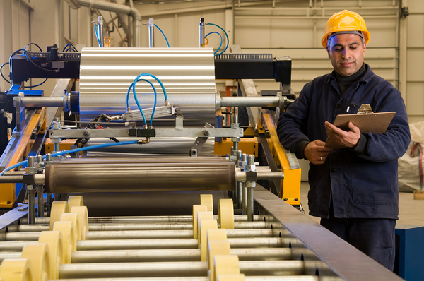 Technician writing on a clipboard next to machinery.