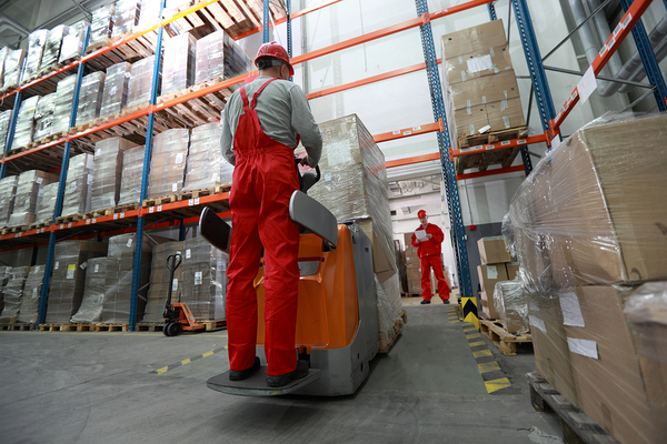 Worker moving large boxes with a machine.