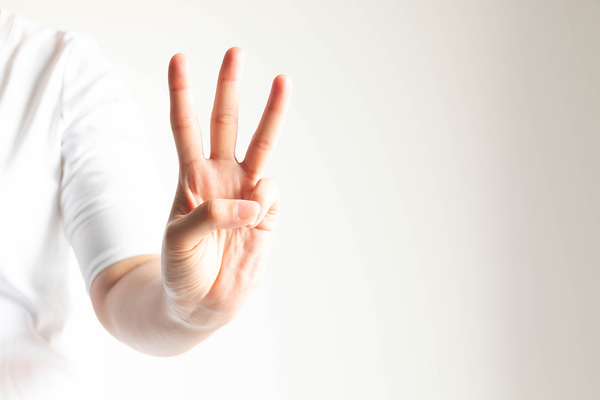 Person holding up three fingers.