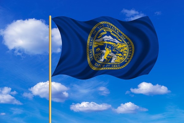 Nebraska state flag with blue sky and clouds in the background