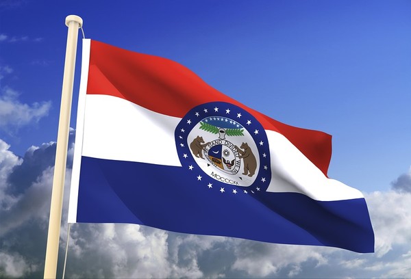 Missouri state flat flying with blue sky and white clouds in the background