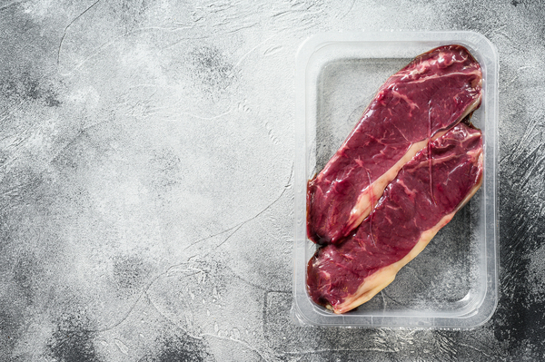 Steaks in a plastic container.