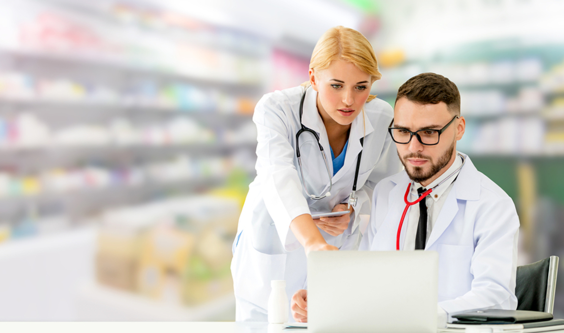 Two medical doctors discussing information displayed on a laptop. Two medical doctors discussing information displayed on a laptop.