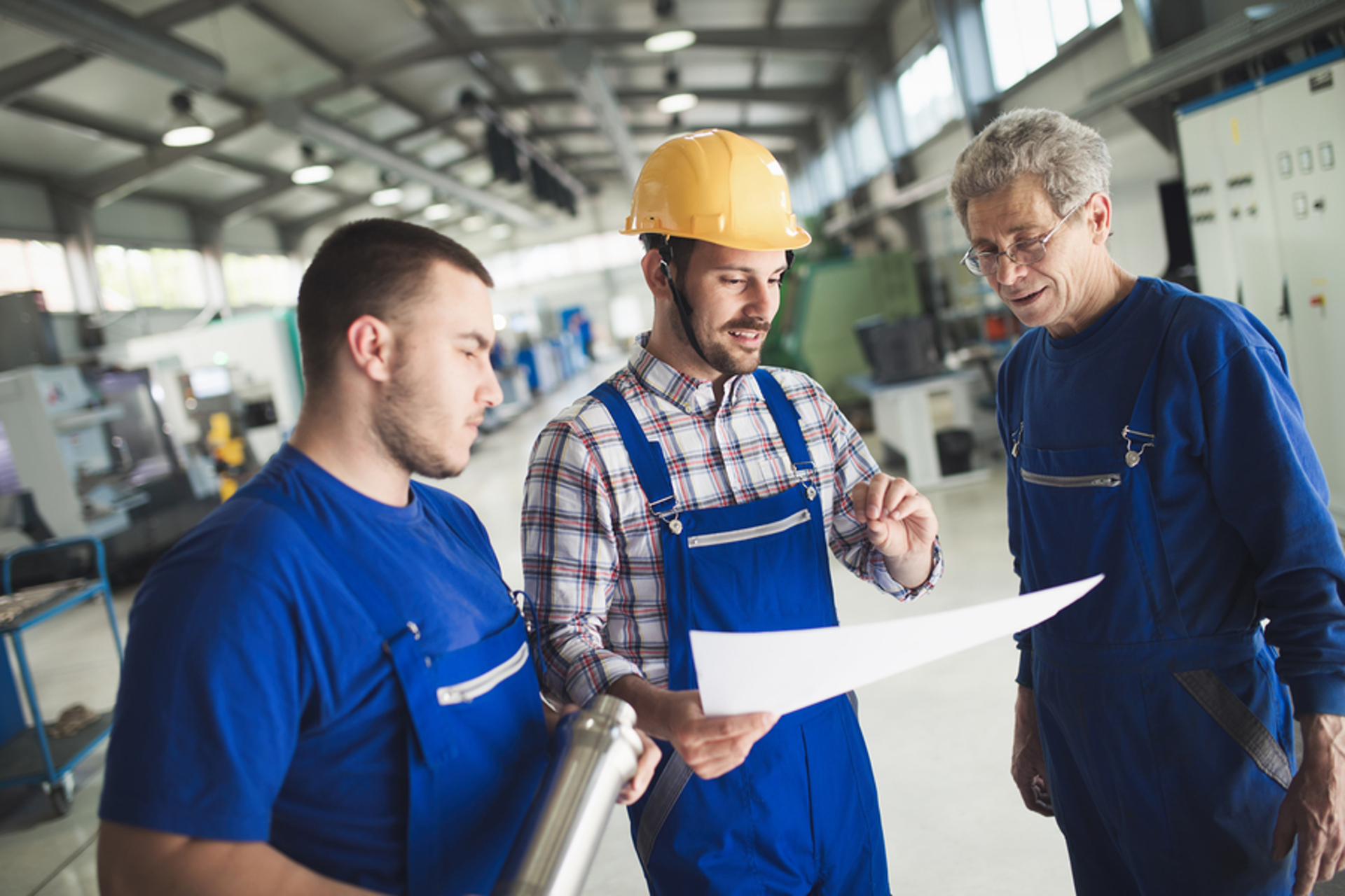 Three men discussing over a sheet of paper.