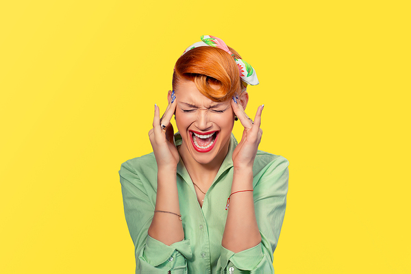 Woman placing her hands at her temples and screaming in frustration.