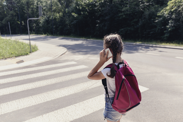 Teenager talking on a phone while walking in a cross walk.