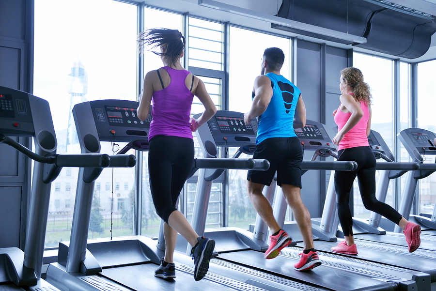 three adults running on a treadmill, showing an example of how a fitness center management might engage with members