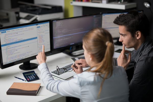 Two people looking at code.