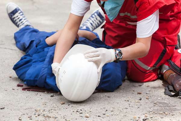 Construction supervisor assisting a worker lying on the ground