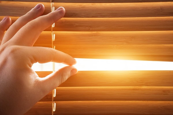 Person opening up blinds to a window.