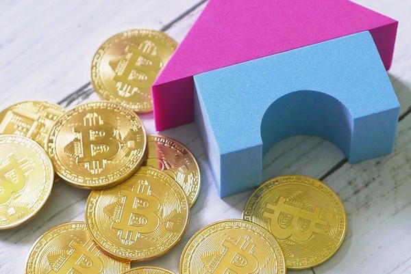 Gold coins with bitcoin symbol and play blocks forming a house.