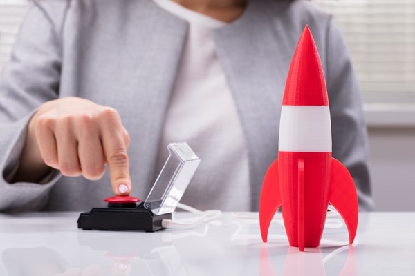 Person pushing a button to launch a miniature rocket.