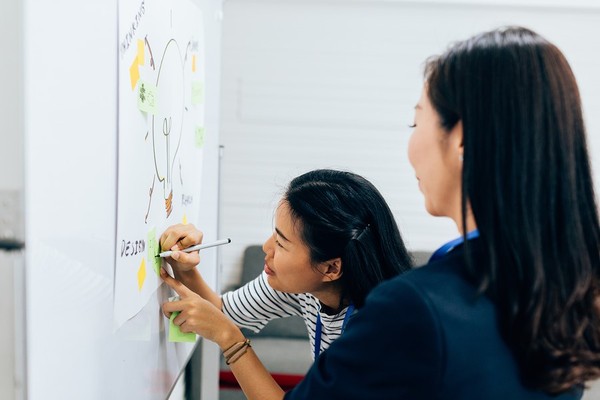 Two women drawing a diagram.