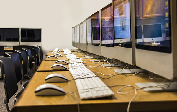 Row of iMacs on multiple desks with keyboards and mice Rameez Khizer, IT Marketing