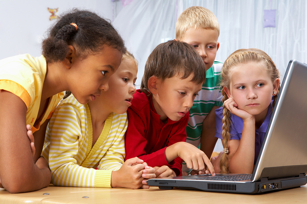 Group of children looking at a laptop computer screen.