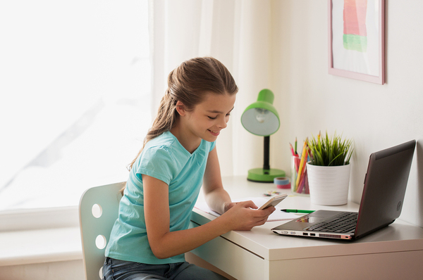 Young teen smiling while looking at her phone.